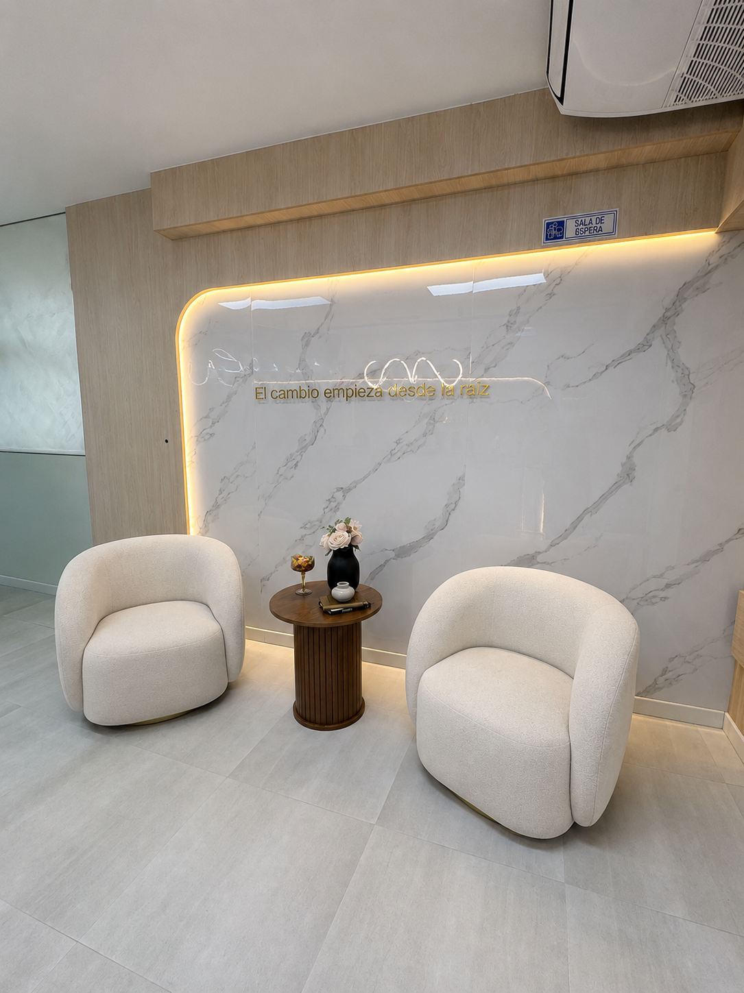 Sala de espera de Recupera: sillones blancos frente a un muro de mármol con la frase “El cambio empieza desde la raíz”