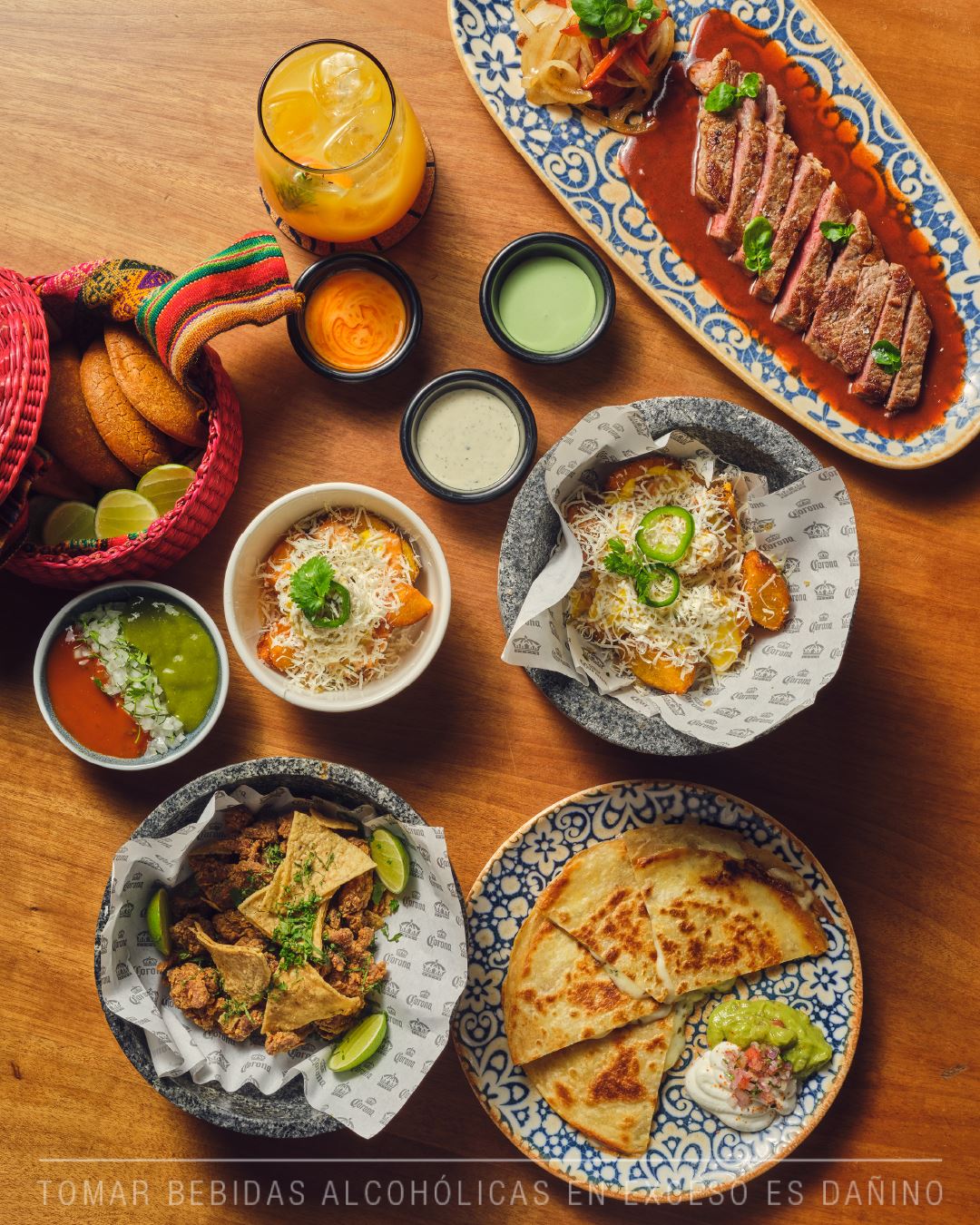 Mesa servida en Vista Corona: corte de res en salsa, quesadillas con guacamole, papitas con queso y salsas taqueras