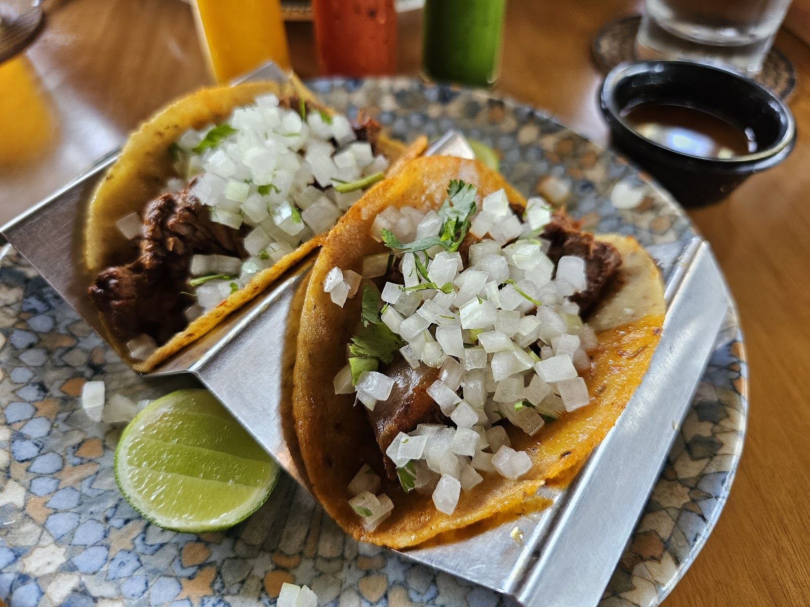 Tacos de birria con cebolla, cilantro, limón y consomé